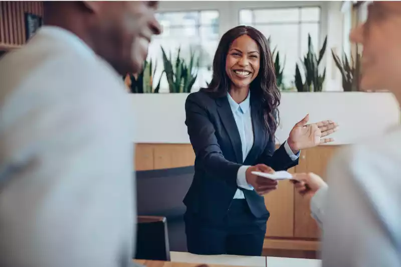 Smiling hotel manager greeting a guest at the front desk
