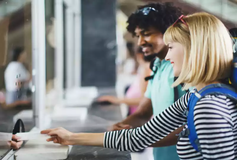 Smiling travelers handing documents to an airline agent at a check-in counter